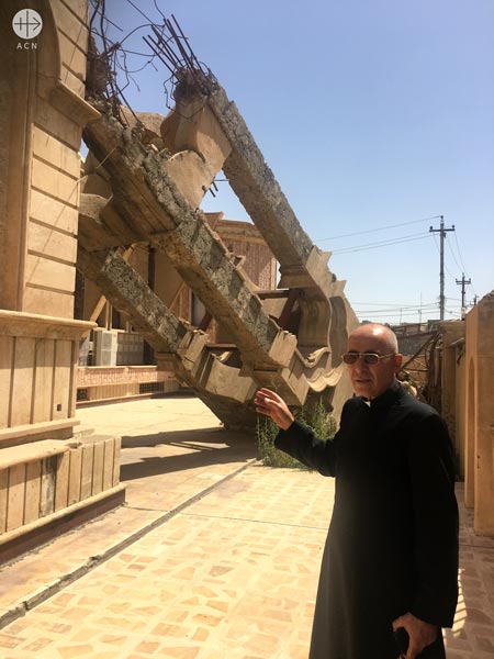 Syriac Catholic parish priest Father Georges Jahola in front of the bell tower ISIS destroyed.