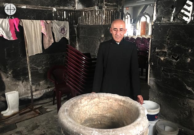 Fr. Georges Jahola showing the font at the Syriac Catholic Mar Behnam Church. The church was heavily damaged by ISIS
