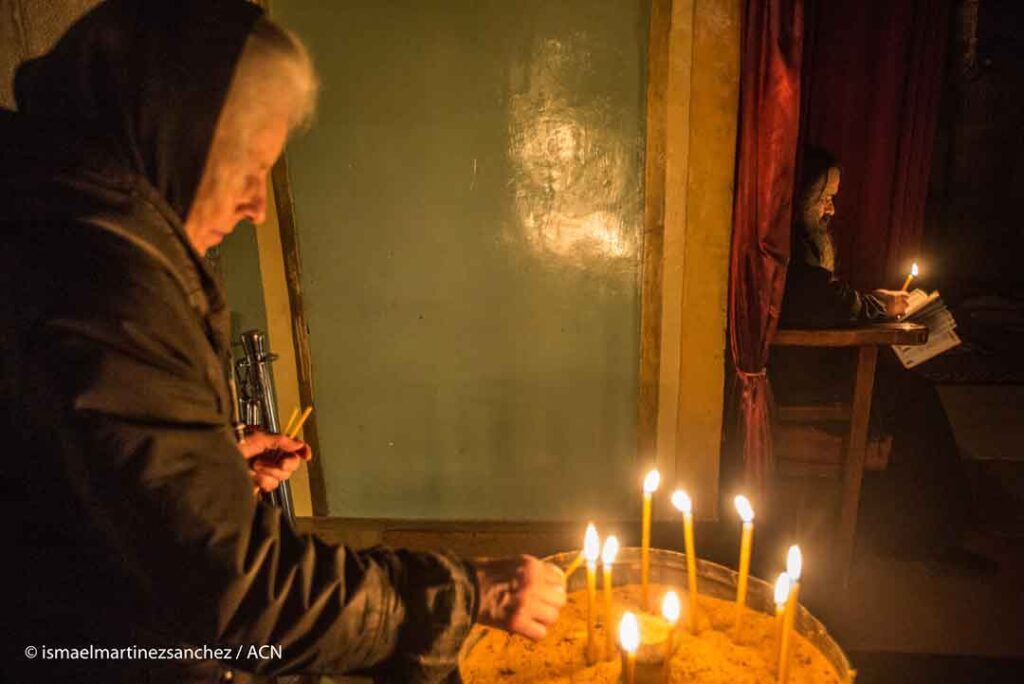Una peregrina ortodoxa griega enciende una vela - Jerusalén