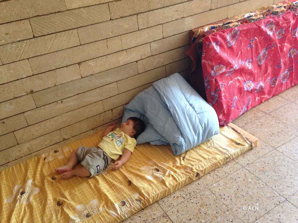 Un niño refugiado durmiendo en un colchón en el suelo de la catedral de San José en Ankawa