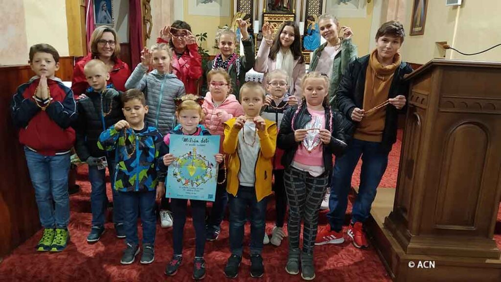 Un grupo de niños con rosarios y un cartel de la campaña "Un millón de niños" en Eslovaquia