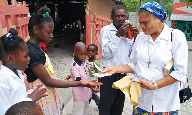 A sister in Bainet parish distributes cards written by French ACN donors to children.